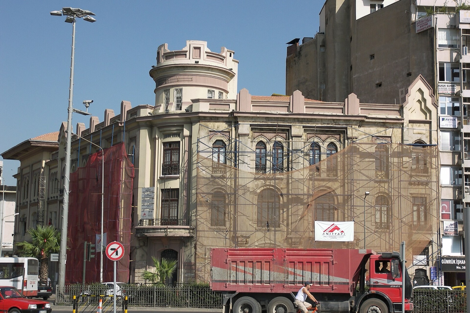 İzmir'de iskele kurulmuş eski bir binanın önünden geçen kırmızı damperli kamyon